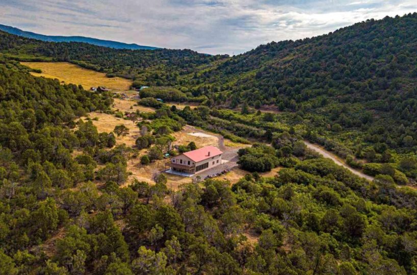 Aerial view of Bearslide Ranch luxury hunting lodge on 919 acres of pristine Colorado wilderness, surrounded by forested hills and open meadows.